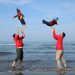 a group of people standing on top of a beach next to the ocean